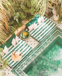 an aerial view of a green and white striped table with food on it, surrounded by palm trees