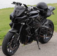 a black motorcycle parked on the side of a road next to a grass covered field