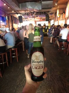 a person holding up a beer in a bar