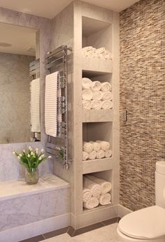 a white toilet sitting next to a bath tub in a bathroom under a large mirror