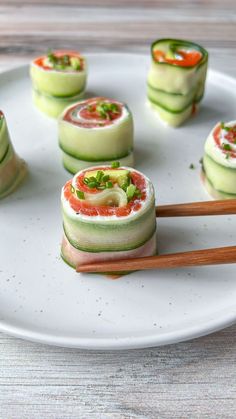 cucumber rolls are arranged on a plate with chopsticks