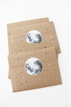 three envelopes with the moon and stars painted on them, one is brown paper