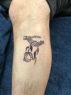 a man with a tattoo on his leg that is holding a rope and flowers in it