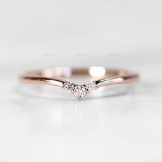 a rose gold ring with two diamonds on it, sitting on a white table top