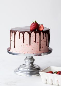 a strawberry cake with chocolate drizzle and strawberries on the top is ready to be eaten