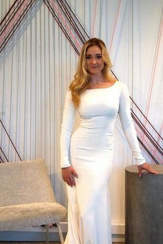 a woman in a long white dress posing for a photo with her hands on her hips