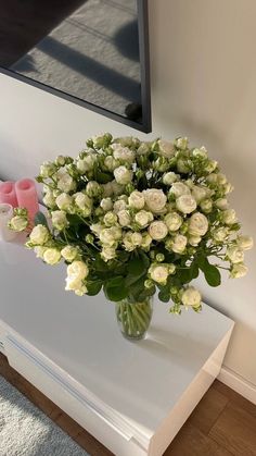 a vase filled with white flowers sitting on top of a table next to a mirror