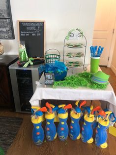 a table topped with lots of blue and yellow rain boots next to a white table cloth