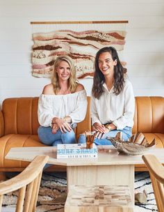 two women sitting on a couch in front of a coffee table