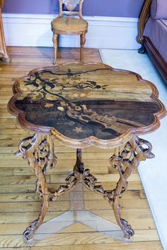 a wooden table sitting on top of a hard wood floor next to a purple couch