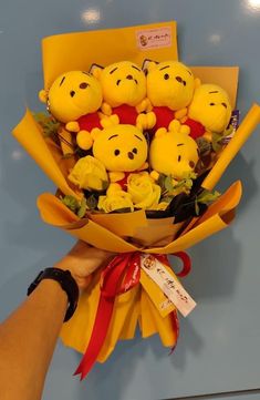 someone holding a bouquet of winnie the pooh stuffed animals