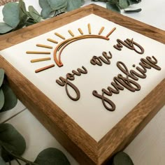 a cake with the words you are sunshine written in frosting on it, surrounded by greenery