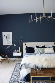 a bedroom with dark blue walls and white bedding, fur rugs on the floor