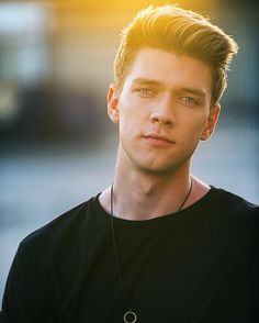 a young man wearing a black shirt and necklace