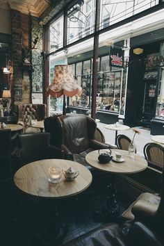 the interior of a coffee shop with leather chairs and tables in front of large windows