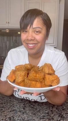 a woman holding a plate with fried food on it