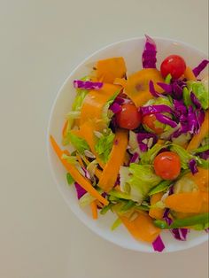 a white plate topped with lettuce, tomatoes and other vegtables