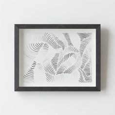 a black and white framed art piece with wavy lines in the center on a wall