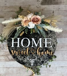 a sign that says home sweet and home on the side of a wall with flowers