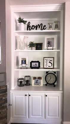 a white bookcase with some pictures on top of it and an alarm clock in the middle