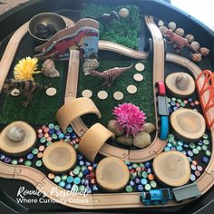 a toy train set sitting on top of a black table covered in rocks and dirt