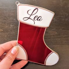 a hand holding a christmas stocking ornament with the word lea on it