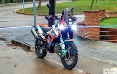 an orange and black motorcycle parked on the side of a road next to a street light