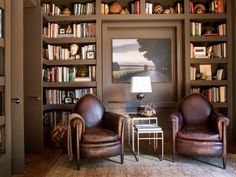 two leather chairs sitting in front of a bookshelf