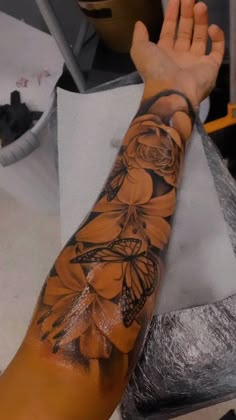 a man's arm with a butterfly and flower tattoo on the left side of his arm