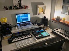 a laptop computer sitting on top of a desk next to a keyboard and sound board