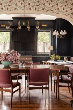 a dining room table and chairs in front of a window with floral wallpaper on the walls