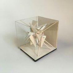 an origami sculpture in a glass box on a white surface with no background