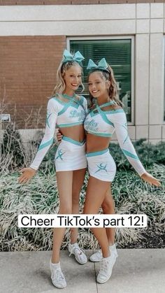 two cheerleaders posing in front of a building with their arms around each other