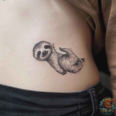 a sloth tattoo on the side of a woman's stomach, with an image of a baby sloth hanging from it