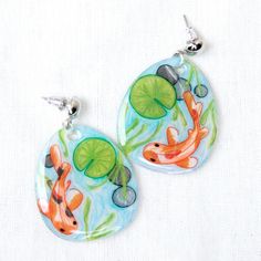 two earrings with fish and lily pads on them