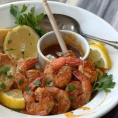 a white plate topped with shrimp and lemon wedges