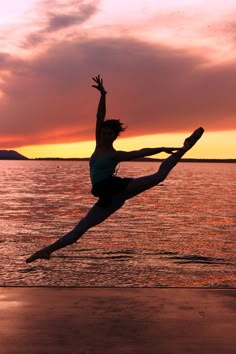 a woman is dancing on the beach at sunset