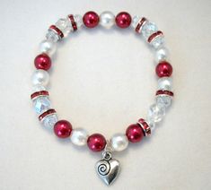 a red and white beaded bracelet with a heart charm