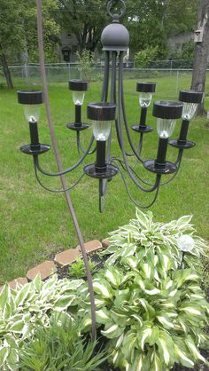 a black chandelier is in the middle of a garden