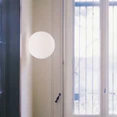 a white door with a round light hanging from it's side next to a window