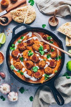 a skillet filled with meatballs covered in sauce and garnished with cilantro