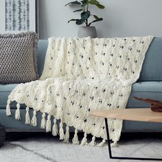 a white crocheted afghan draped over a blue couch next to a coffee table