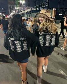 two women walking down the street in front of some people wearing shirts with numbers on them