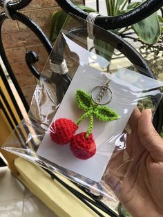 a pair of earrings with crocheted flowers on them are being held up by someone's hand