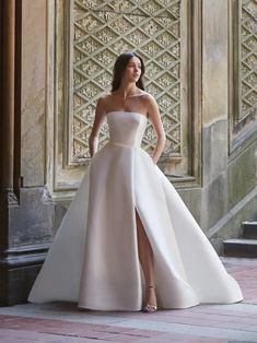 a woman standing in front of a building wearing a white dress