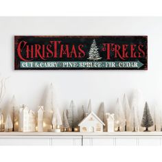 a wooden sign that says christmas trees and lit candles in front of a fireplace mantel