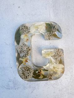 the letter g is made out of glass with flowers and leaves on it's sides