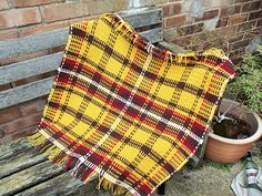 a blanket sitting on top of a wooden bench next to a potted planter