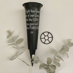 a black vase sitting on top of a white table next to a clock and flowers