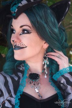 a woman with green hair and black cat ears wearing an elaborate necklace on her neck